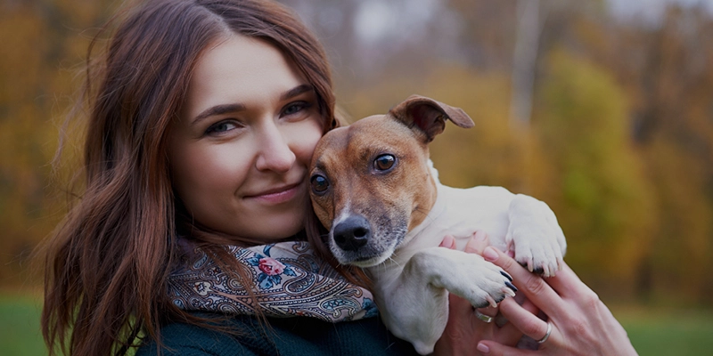 En kvinna som håller en liten hund mot kinden