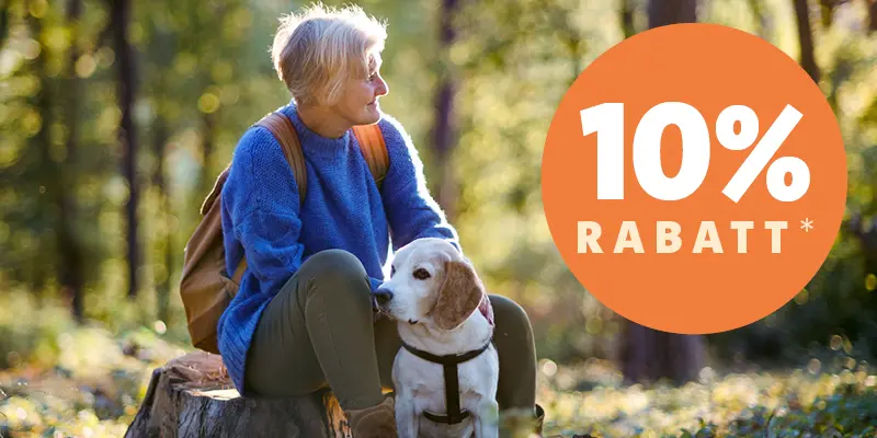 Äldre kvinna med en hund i skogen och en skylt med erbjudande om 10 procent rabatt